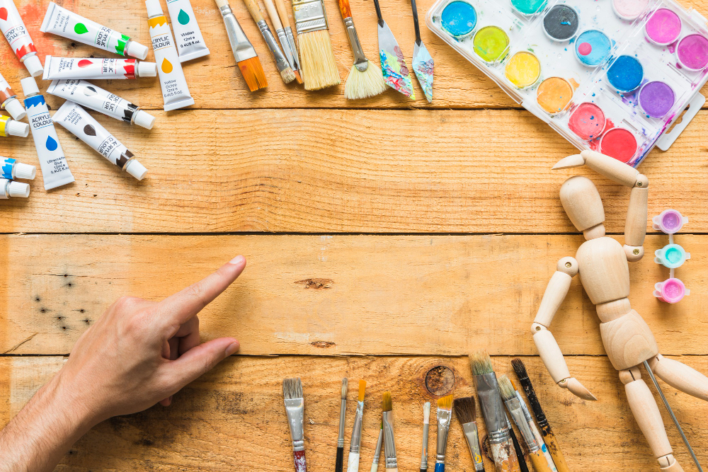 mesa de trabajo para talleres creativos. llena de pinturas en pomo y pinceles listos para un trabajo artesanal y artístico único
